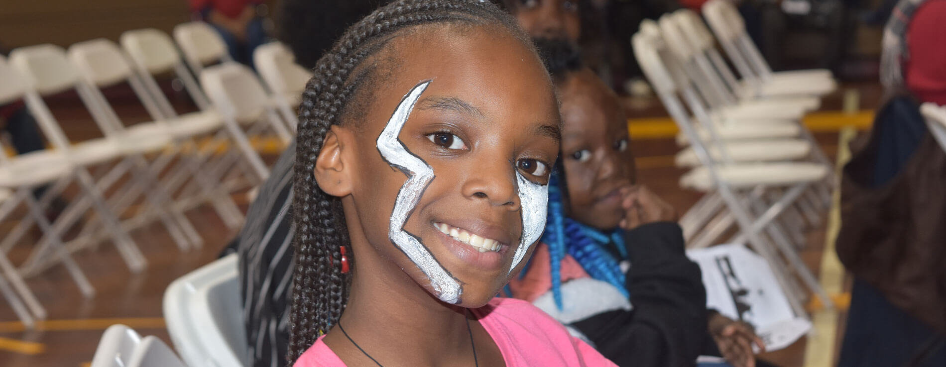A child smiling while showing off her face paint.